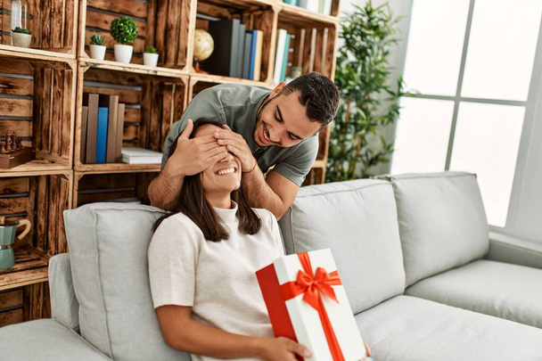 Молодой человек удивляет свою девушку подарком на день рождения дома. - Фото, изображение