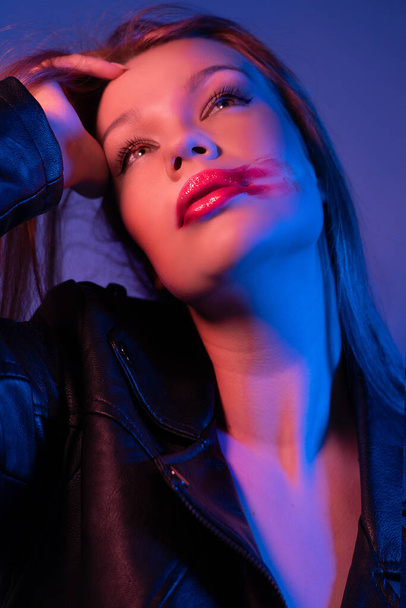 A girl with a bright lipstick smeared on her cheek, she has long hair Photoshoot in blue-pink light - Fotoğraf, Görsel