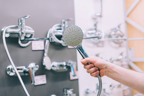 A man in a hardware store chooses a faucet for a shower stall - 写真・画像