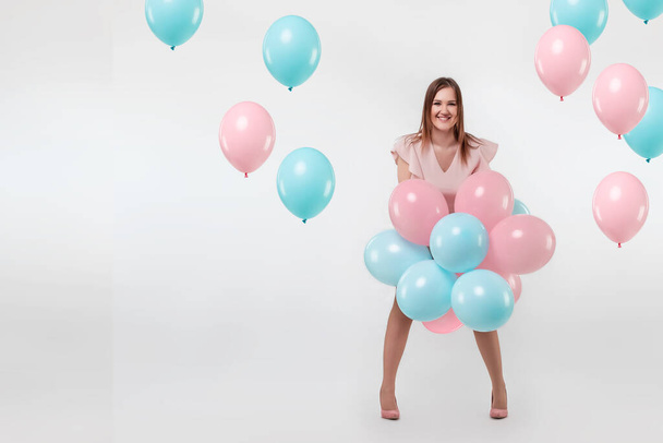 Beautiful young girl with with blue and pink balloons on the background, Joyful model. Happiness, spring, birthday party - Φωτογραφία, εικόνα