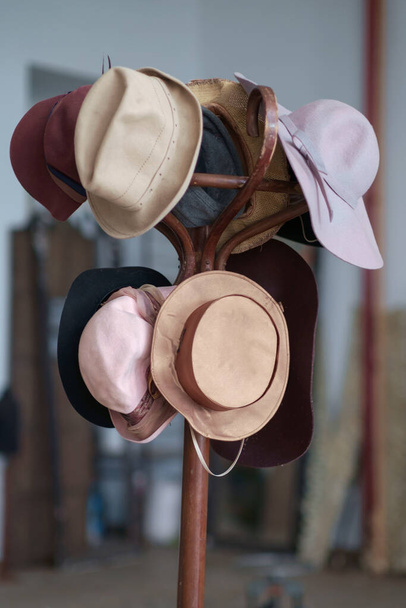 Erilaisia vintage värikkäitä hattuja roikkuu puinen ruskea takki teline, valikoiva painopiste - Valokuva, kuva