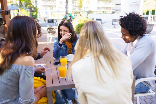Πολυεθνική ομάδα φίλων που πίνουν ένα ποτό μαζί σε υπαίθριο μπαρ. - Φωτογραφία, εικόνα