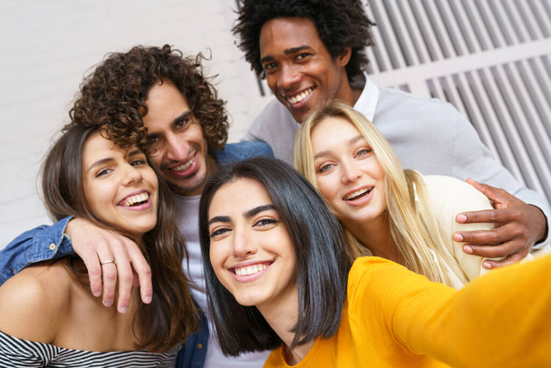 Grupo multiétnico de amigos tomando una selfie juntos mientras se divierten al aire libre. - Foto, Imagen