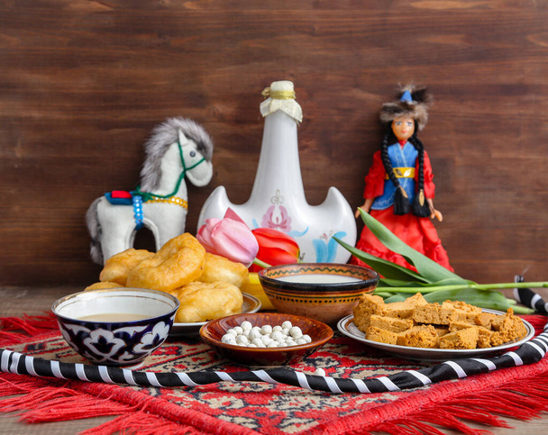 Bodegón kazajo en Nauryz, con comida nacional: baursaks, irimshik, kurt, koumiss y té sobre un fondo de madera - Foto, imagen