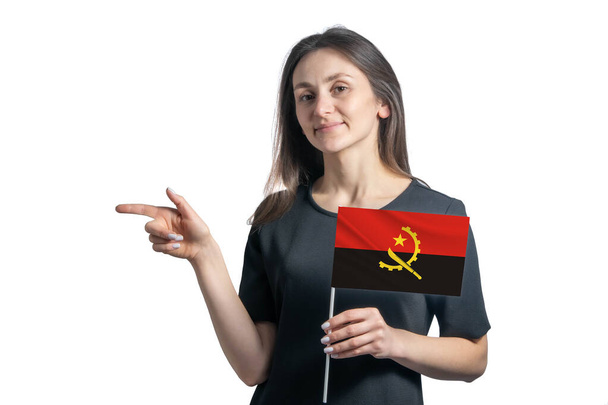 Happy young white woman holding flag Angola and points to the left isolated on a white background. - Photo, Image