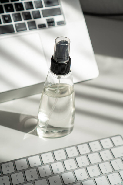 a jar of sanitizer on an office table among computer technology - Foto, afbeelding