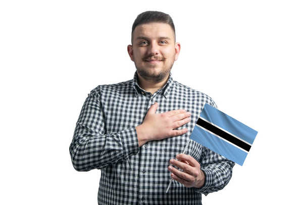 White guy holding a flag of Botswana and holds his hand on his heart isolated on a white background With love to Botswana. - Photo, Image