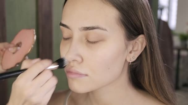 make up artist facendo il trucco per bruna donna asiatica con pennello nel salone di bellezza - Filmati, video