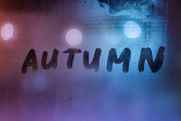 la palabra otoño escrito a mano en la superficie de cristal de la ventana húmeda noche - Foto, imagen