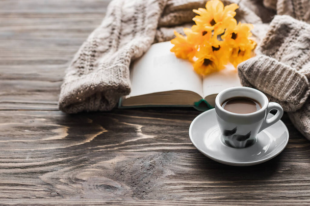 Café matutino. Una taza de café sobre una mesa de madera, un libro abierto y un suéter caliente sobre el fondo de un ramo de flores de primavera. Concepto de naturaleza muerta. Acogedora mañana. - Foto, imagen