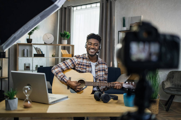 Inspired afro man playing guitar and recording video - Φωτογραφία, εικόνα