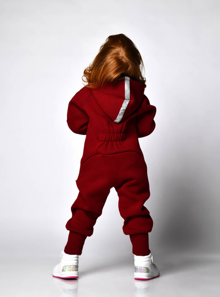 Rear view of red-haired preschooler girl wearing warm tracksuit studio portrait - Photo, Image