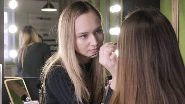 attraente caucasico make up artista fare trucco per asiatico ragazza in bellezza salone - Filmati, video