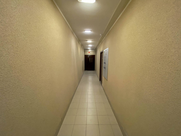 Long couloir avec portes en métal, mur carrelé et plancher. - Photo, image