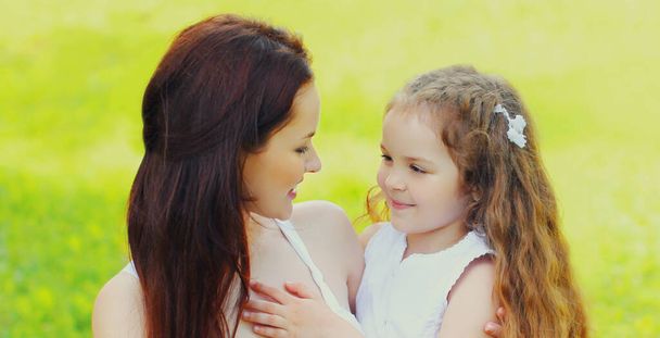 Portrait of beautiful happy smiling mother with little girl child on the grass in a summer park - Photo, Image