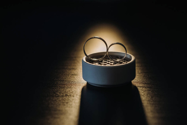 two gold wedding rings in a white box on a black background. - 写真・画像