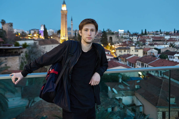 An intelligent young European man against backdrop of Antalya at night in Turkey. - Фото, изображение