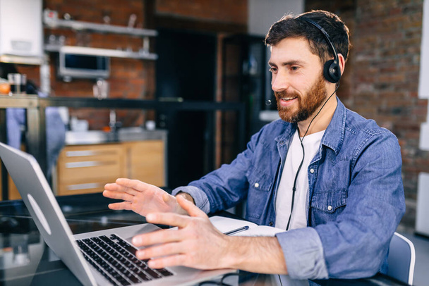 call center worker working together with a smile on his face using a headset. Young handsome man smiling in the office. - Foto, imagen