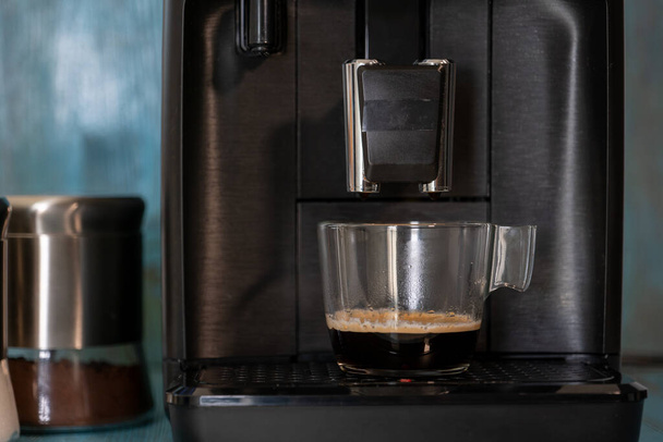 coffee machine makes espresso on blue wooden background - Fotoğraf, Görsel