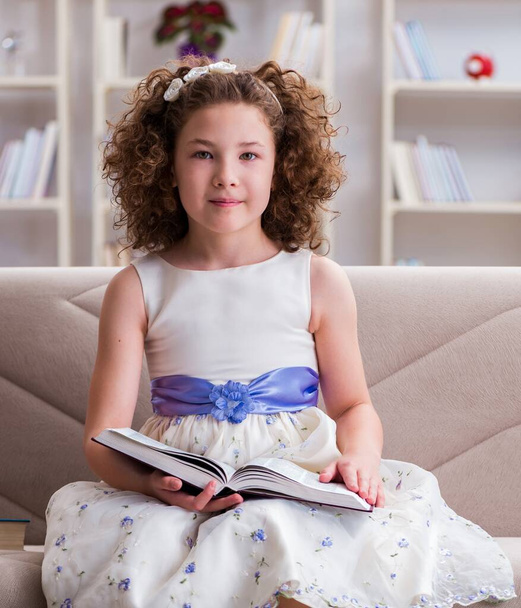 Μικρό όμορφο κορίτσι διαβάζει βιβλία στο σπίτι - Φωτογραφία, εικόνα