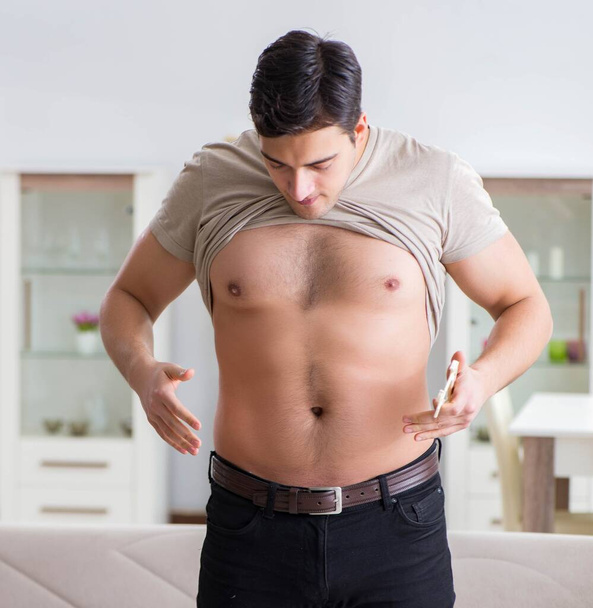 Hombre midiendo grasa corporal con pinzas - Foto, imagen
