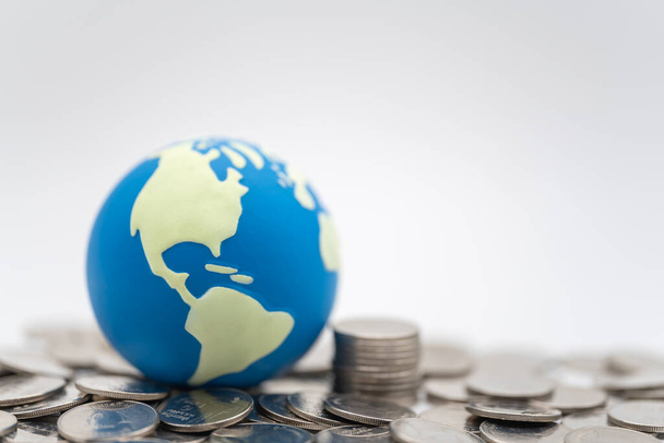 Money Global Business Concept. Gros plan de mini boule du monde sur pile et pile de pièces d'argent sur fond blanc. - Photo, image