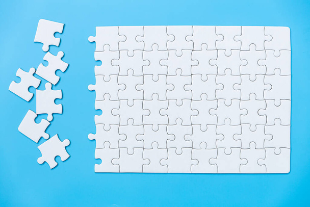 Unfinished white jigsaw puzzle pieces on blue background, The last piece of jigsaw puzzle, Copy space. - Photo, Image