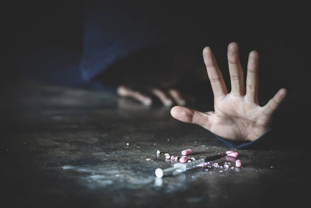  Un uomo ddict con una siringa usando droghe sul pavimento. Concetto di dipendenza da droghe e sintomi di astinenza. drogheGiornata internazionale contro l'abuso di droghe. - Foto, immagini