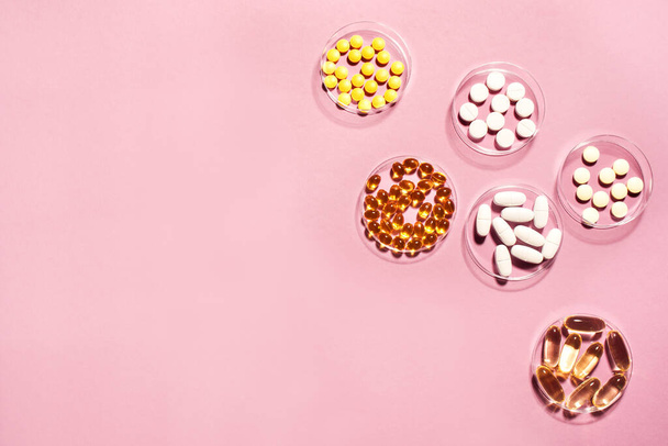 Vitamins capsules on pink background, top view, copy space. Food supplements: fish oil, omega 3, omega 6, omega 9, vitamin A, D3,  E, B, calcium. - Photo, Image