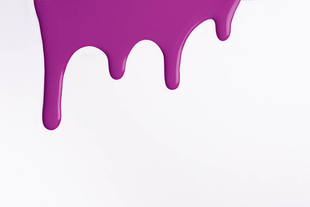 Des gouttes liquides pourpres pâles de peinture coulent sur un fond blanc isolé. Fond lilas abstrait avec motif fluide goutte à goutte. Peinture acrylique violette avec espace de copie. - Photo, image