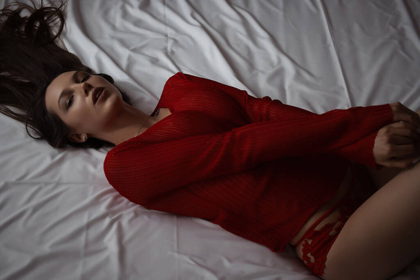 Back view of slim sexual nude woman in panties lying on bed in room - Fotó, kép