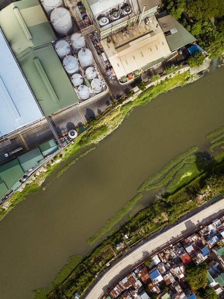 Marikina Nehri 'nin en üst manzarası ve bir tarafta yiyecek ve özel yağlar depolama tesisi ve karşı kıyıda gecekondu mahalleleri.. - Fotoğraf, Görsel