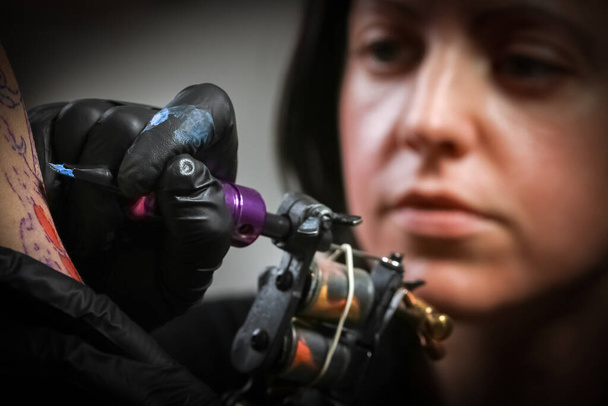 Femme tatoueuse faisant un tatouage sur le bras d'un homme
 - Photo, image