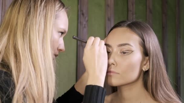 привлекательная кавказская визажистка делает макияж для азиатки в салоне красоты - Кадры, видео