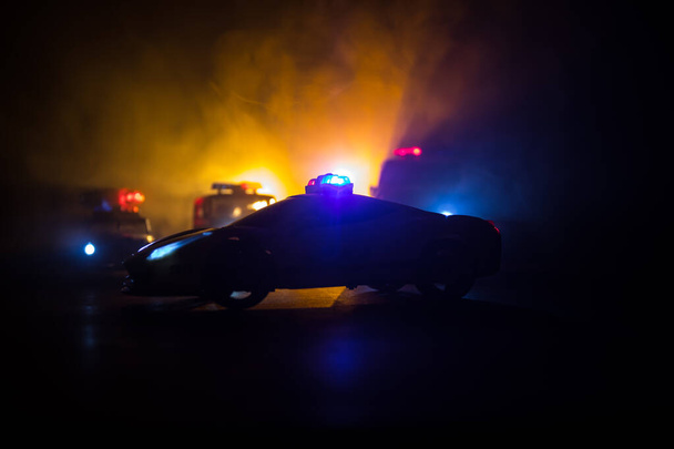 Radiowóz ściga samochód w nocy z mgłą w tle. Policyjny radiowóz ratowniczy jedzie na miejsce zbrodni. Kreatywna dekoracja. Skupienie selektywne - Zdjęcie, obraz