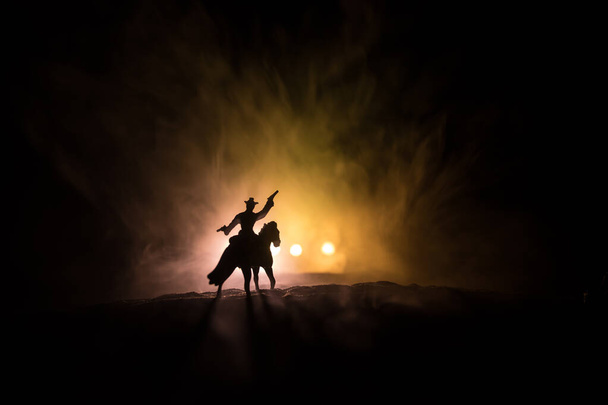 Western concept. Battle between cowboys at night. Duel to the death. Creative artwork decoration on toned foggy background in selective focus - Fotó, kép