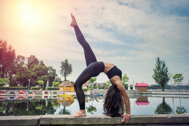 Young slim woman doing yoga exercises near lake.  Concept of calm and meditation - Photo, Image