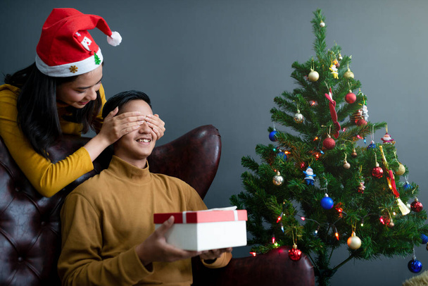 Asyalı kadınlar erkek arkadaşına Noel hediyesi veriyor. Mutlu Noeller ve mutlu yıllar. - Fotoğraf, Görsel