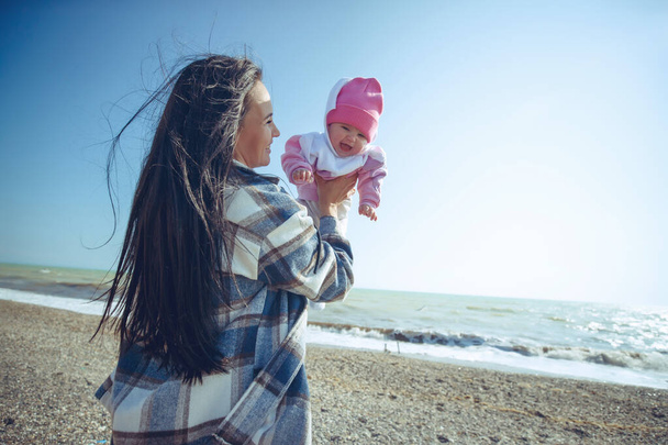 Egy nő egy gyerekkel a tengernél. Gyönyörű anya játszik a kisbabájával a tenger mellett.. - Fotó, kép