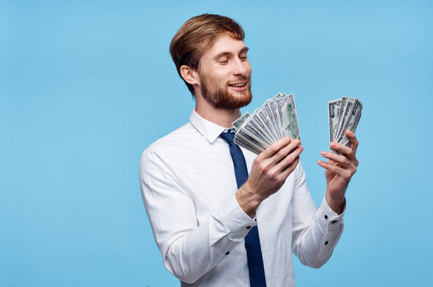 uomo ricco in giacca e cravatta con soldi in mano emozioni sfondo blu - Foto, immagini