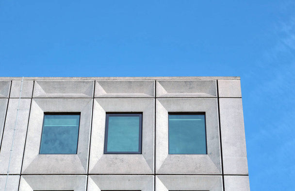 perspectief uitzicht op een wit betonnen kantoorgebouw tegen een helderblauwe hemel met geometrische brutalistische jaren zestig details - Foto, afbeelding