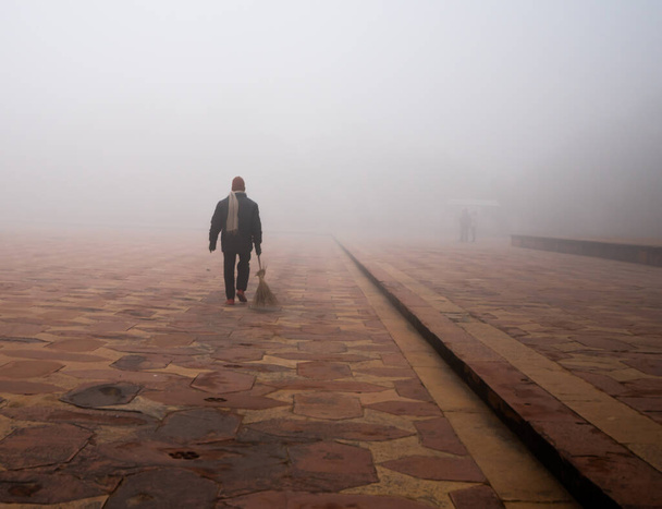A back view of a janitor walking on a foggy day - Photo, Image