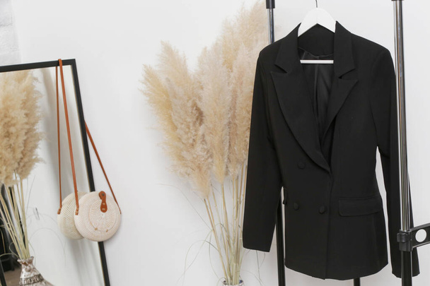 Women's Clothes. Clothes rack, black blazer in fashion atelier. - Photo, Image