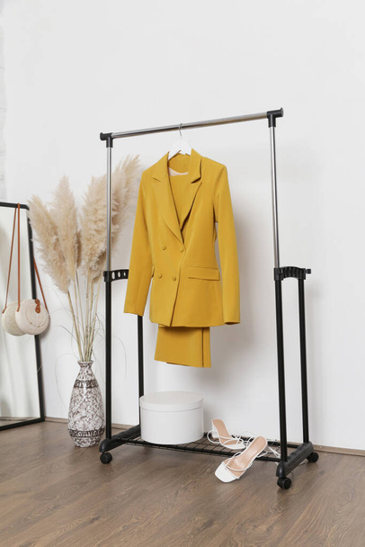 Frauenkleidung. Kleiderständer, gelber Anzug und Schuhe im Modeatelier. - Foto, Bild