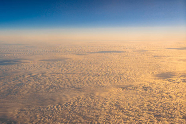 kultainen pilvi sinisen taivaan yllä Ylhäällä näkymä lentokoneen sivuikkunoista auringonnousun, maisemankannen, mainoksen ja mallinnuksen, kuljetuksen ja matkustajan konseptin yhteydessä - Valokuva, kuva