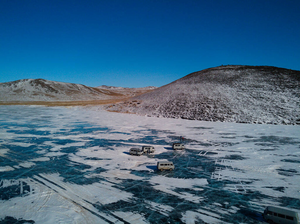 egy drónkép régi szovjet autókról, amik a Bajkál-tó jegén állnak az Olkhon-sziget partjainál. Utazás télen Szibéria Oroszország. - Fotó, kép