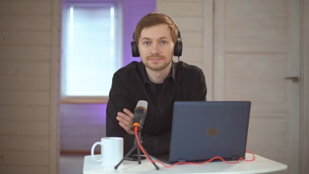 Portret van trendy podcast maker streaming audio-uitzending in zijn huis. Uitzending van een interview met behulp van microfoon - Video