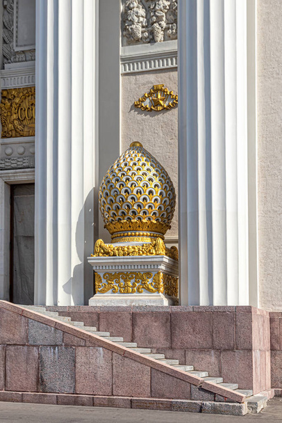 Moscow, Russia, 04.14.2021. Carved decorative egg, covered with gilding, between the columns at the central pavilion No. 1 at VDNH - Photo, Image