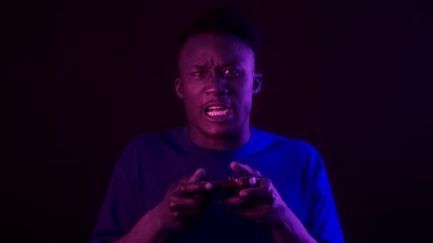 Os jogos de vídeo falham. Jovem afro-americano irritado homem com joystick perder jogo dizendo Venha em luzes de néon roxo - Filmagem, Vídeo