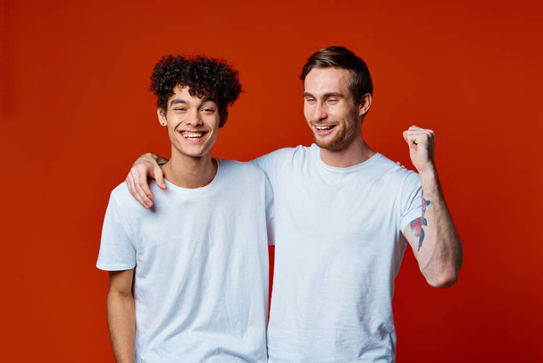 двоє чоловіків у білих футболках веселі емоції руки жести обійми дружби
 - Фото, зображення